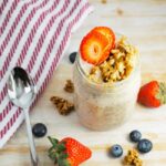 Photo of Banana Cream Pie Overnight Oats in a Mason Jar with a spoon and scattered fruit